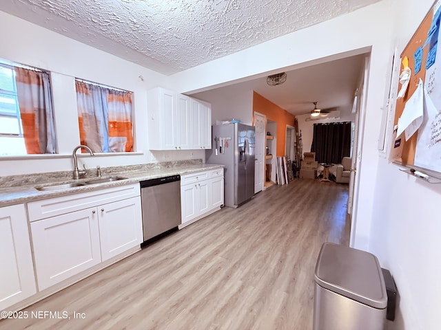 kitchen featuring sink, light hardwood / wood-style flooring, a textured ceiling, stainless steel appliances, and white cabinets