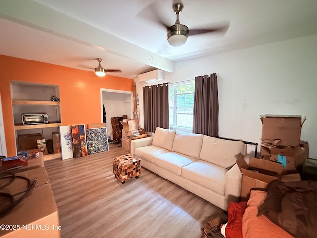 living room featuring beamed ceiling, an AC wall unit, ceiling fan, and light wood-type flooring