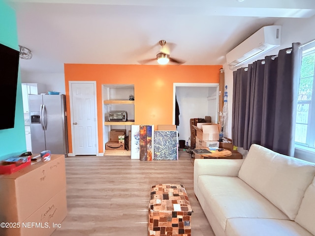 living room featuring a wall unit AC, ceiling fan, and light wood-type flooring