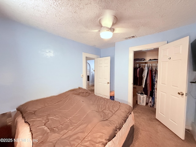 carpeted bedroom featuring ceiling fan, a closet, and a textured ceiling