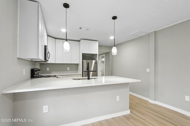 kitchen featuring white cabinetry, pendant lighting, stainless steel appliances, and kitchen peninsula