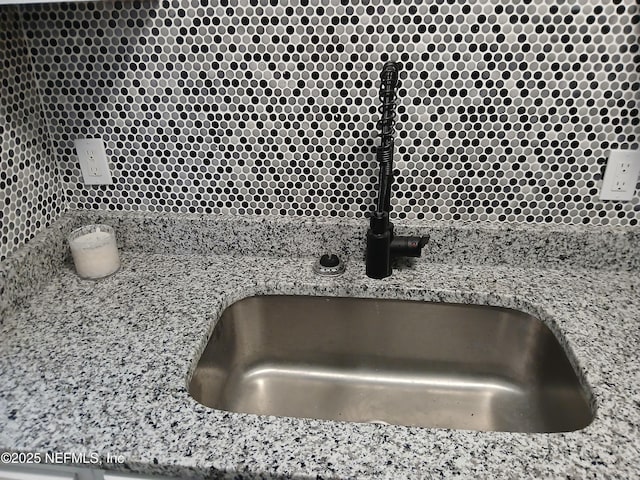 interior details featuring light stone counters and a sink