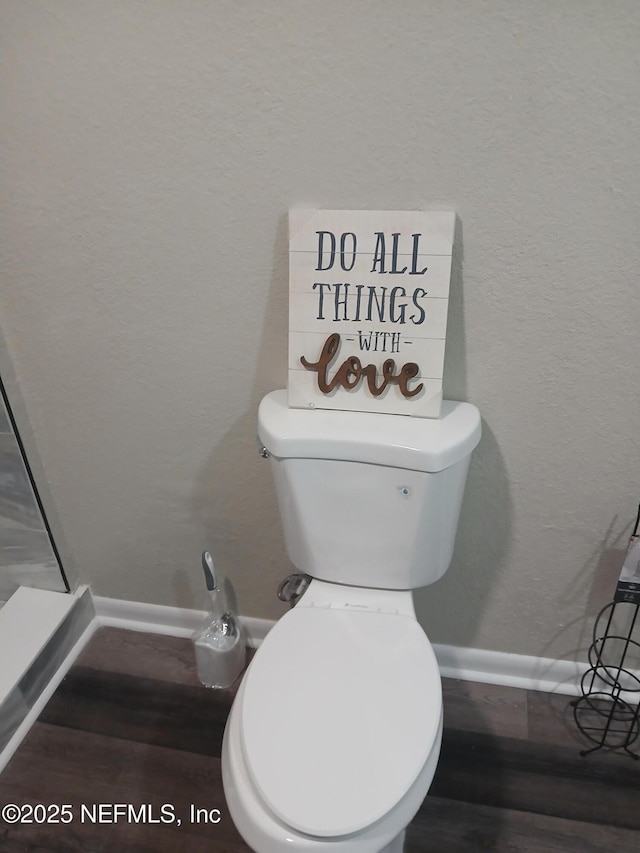 bathroom featuring a textured wall, toilet, and baseboards