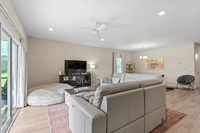 living room featuring ceiling fan with notable chandelier and light hardwood / wood-style floors