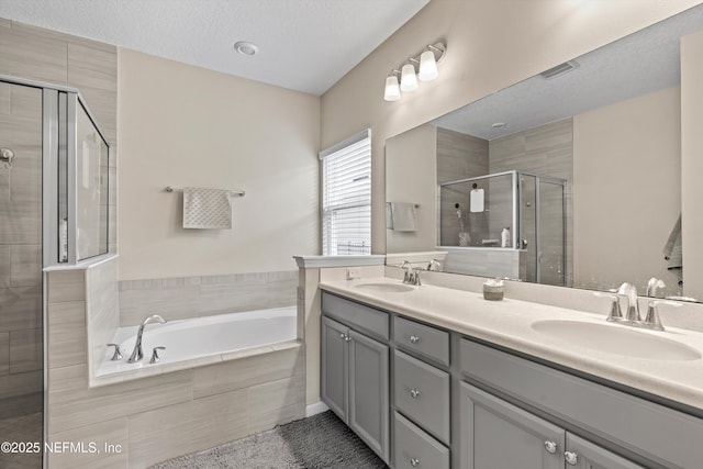 bathroom featuring vanity, plus walk in shower, and a textured ceiling