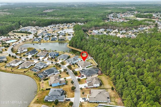 drone / aerial view featuring a residential view, a wooded view, and a water view