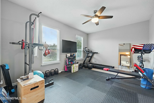 exercise room with ceiling fan, baseboards, and a textured ceiling