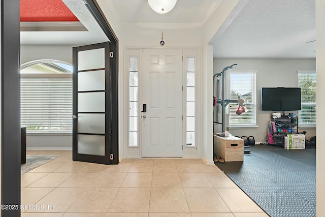 tiled foyer with a textured ceiling and baseboards