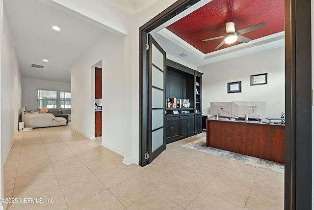 hall featuring a tray ceiling, light tile patterned flooring, recessed lighting, and visible vents