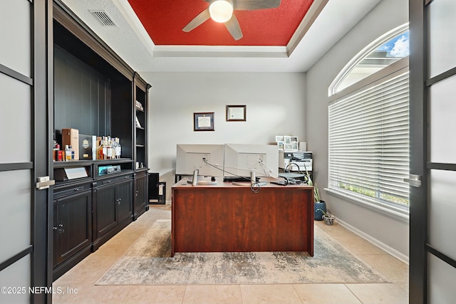 home office with a wealth of natural light, visible vents, a raised ceiling, and light tile patterned floors