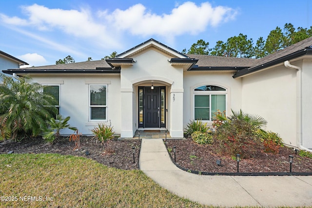 view of front of home with roof with shingles and stucco siding