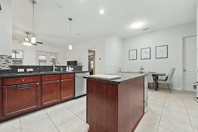 kitchen featuring stainless steel dishwasher, light tile patterned floors, reddish brown cabinets, and a sink