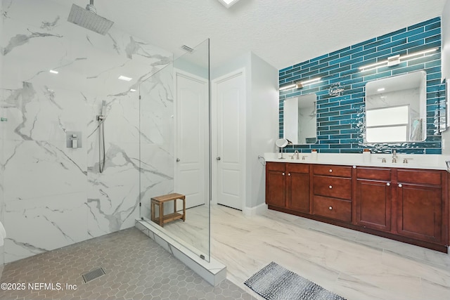 bathroom featuring marble finish floor, a sink, a textured ceiling, a marble finish shower, and double vanity