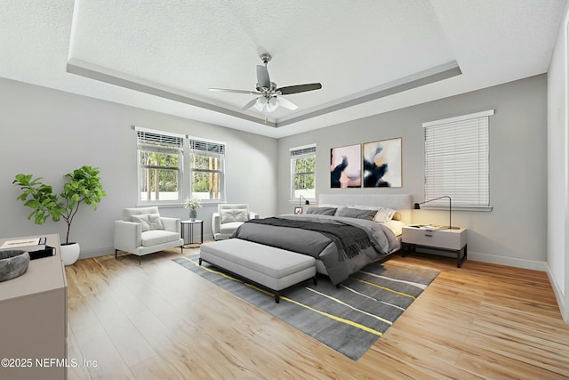 bedroom with a tray ceiling, a textured ceiling, and wood finished floors