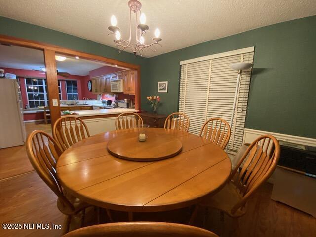 dining area featuring hardwood / wood-style flooring, a textured ceiling, and a notable chandelier