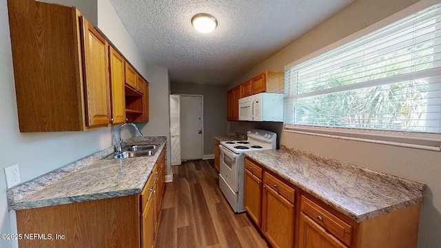 kitchen with white appliances, sink, light hardwood / wood-style flooring, and a textured ceiling