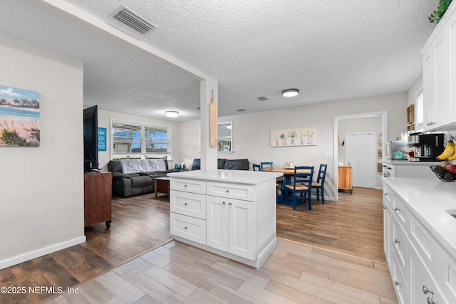 kitchen featuring white cabinetry, a textured ceiling, and light wood-type flooring