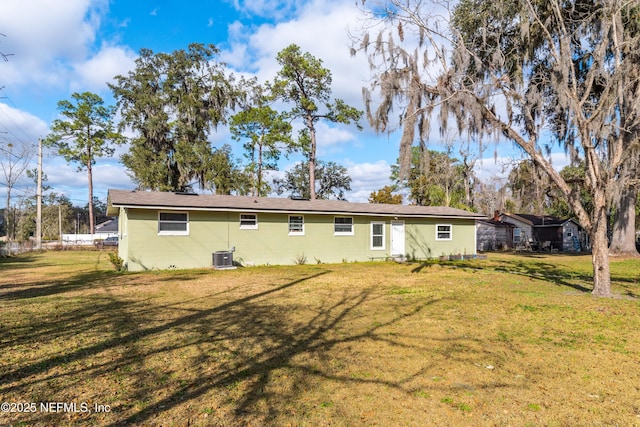 rear view of property with central AC and a yard