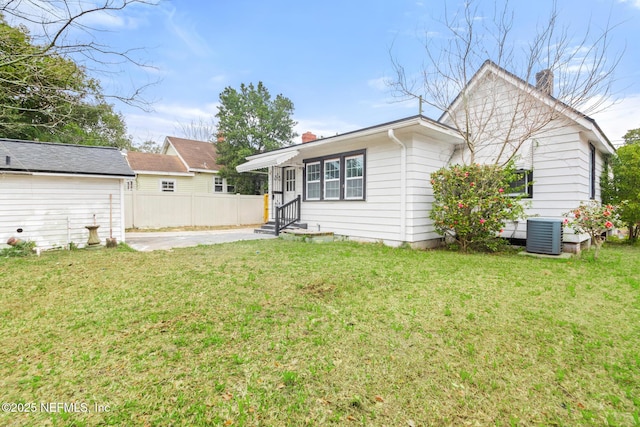 rear view of property featuring cooling unit and a yard