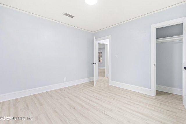 unfurnished bedroom featuring crown molding, light hardwood / wood-style floors, and a closet