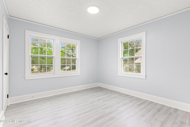 spare room featuring ornamental molding, a textured ceiling, and light wood-type flooring