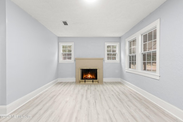 unfurnished living room with a fireplace, light hardwood / wood-style flooring, and a textured ceiling