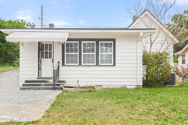 view of front of property with a front lawn and central air condition unit