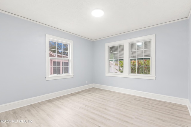 empty room with ornamental molding, plenty of natural light, and light hardwood / wood-style flooring