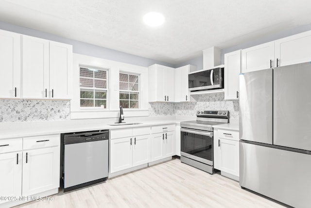 kitchen with stainless steel appliances, white cabinetry, and sink