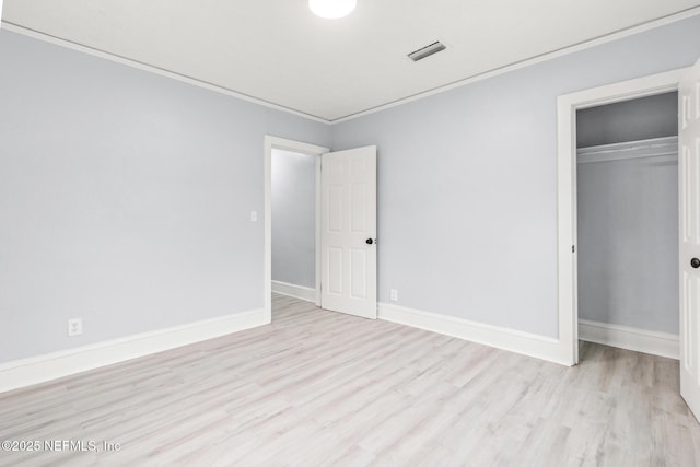 unfurnished bedroom with ornamental molding, light hardwood / wood-style floors, and a closet