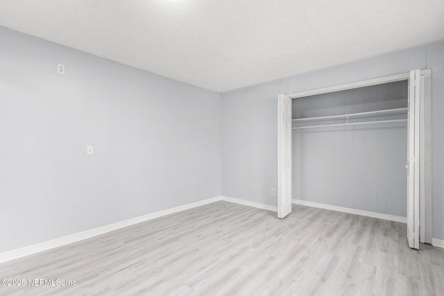 unfurnished bedroom with light wood-type flooring and a closet