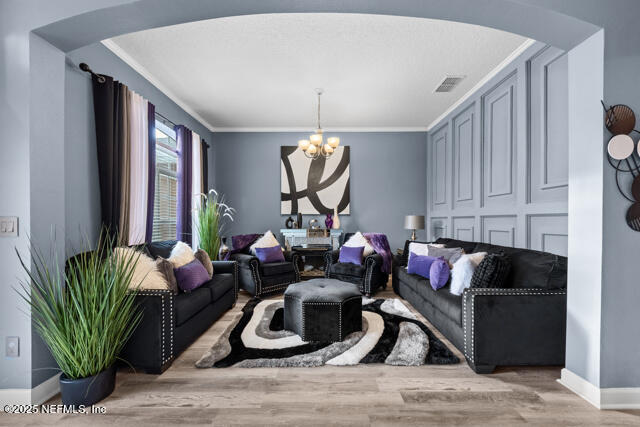 living room featuring crown molding, an inviting chandelier, and light hardwood / wood-style floors