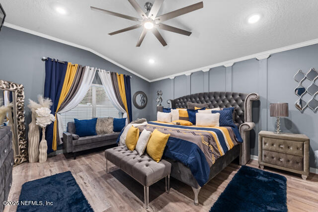 bedroom with hardwood / wood-style flooring, crown molding, lofted ceiling, and ceiling fan