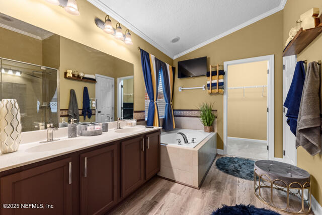 bathroom with lofted ceiling, crown molding, hardwood / wood-style flooring, vanity, and plus walk in shower