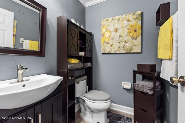 bathroom with ornamental molding, vanity, and toilet