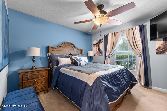 bedroom with ceiling fan, carpet, and a textured ceiling