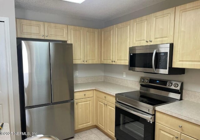 kitchen featuring stainless steel appliances, a textured ceiling, and light brown cabinets