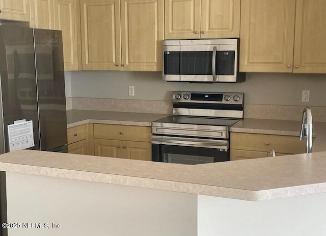 kitchen with appliances with stainless steel finishes, sink, and light brown cabinetry