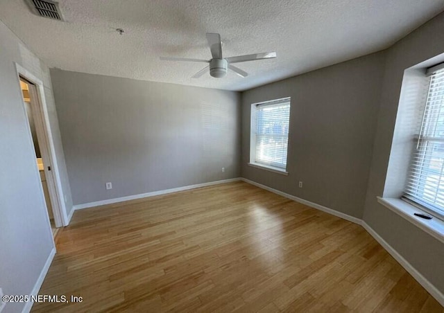 unfurnished room with a textured ceiling, ceiling fan, and light hardwood / wood-style flooring