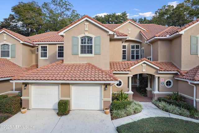 mediterranean / spanish home with a tiled roof, stucco siding, and driveway