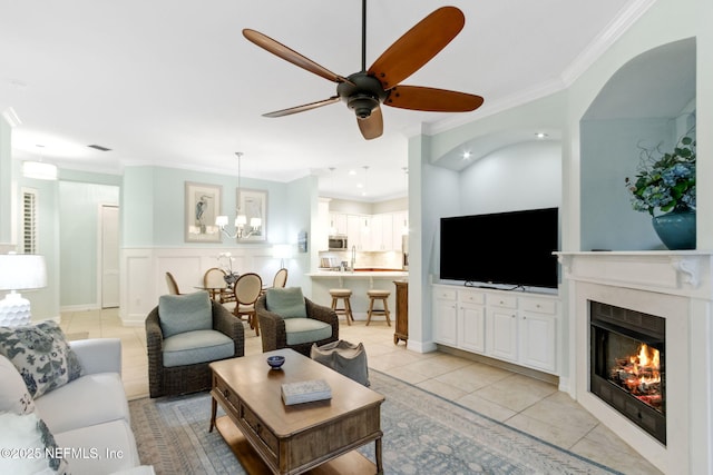 living room featuring a wainscoted wall, a premium fireplace, light tile patterned floors, ornamental molding, and a decorative wall