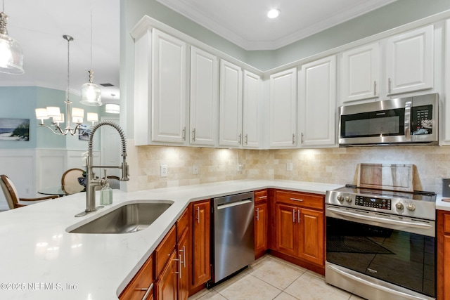 kitchen with light tile patterned floors, a wainscoted wall, a sink, ornamental molding, and stainless steel appliances