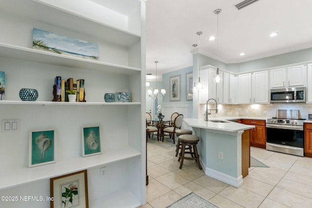 kitchen featuring visible vents, a sink, white cabinets, appliances with stainless steel finishes, and a kitchen bar