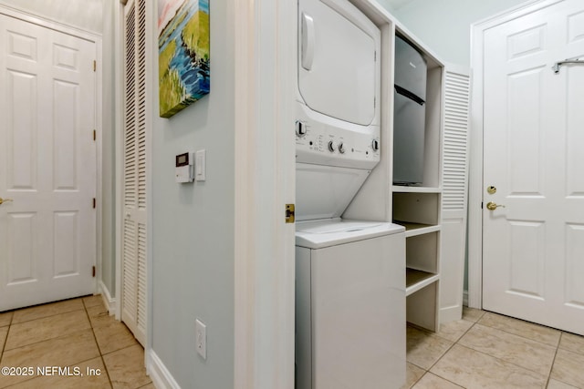 washroom with light tile patterned floors, laundry area, and stacked washer and dryer