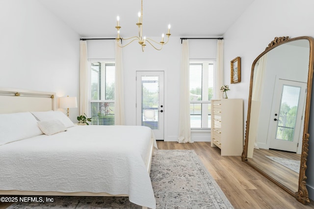 bedroom with access to exterior, a chandelier, and light hardwood / wood-style flooring