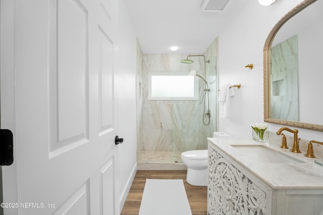 bathroom featuring hardwood / wood-style flooring, vanity, toilet, and a tile shower