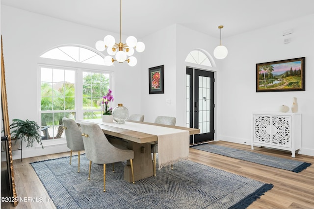 dining area with a notable chandelier, wood-type flooring, and french doors