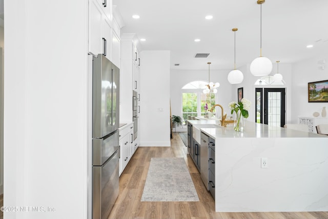 kitchen featuring stainless steel appliances, a large island, pendant lighting, and white cabinets