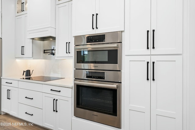 kitchen featuring black electric cooktop, stainless steel double oven, and white cabinets