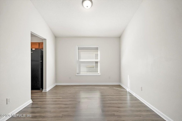 spare room featuring a textured ceiling and dark hardwood / wood-style flooring